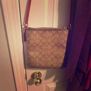 This is a coach signature bag with a red strap